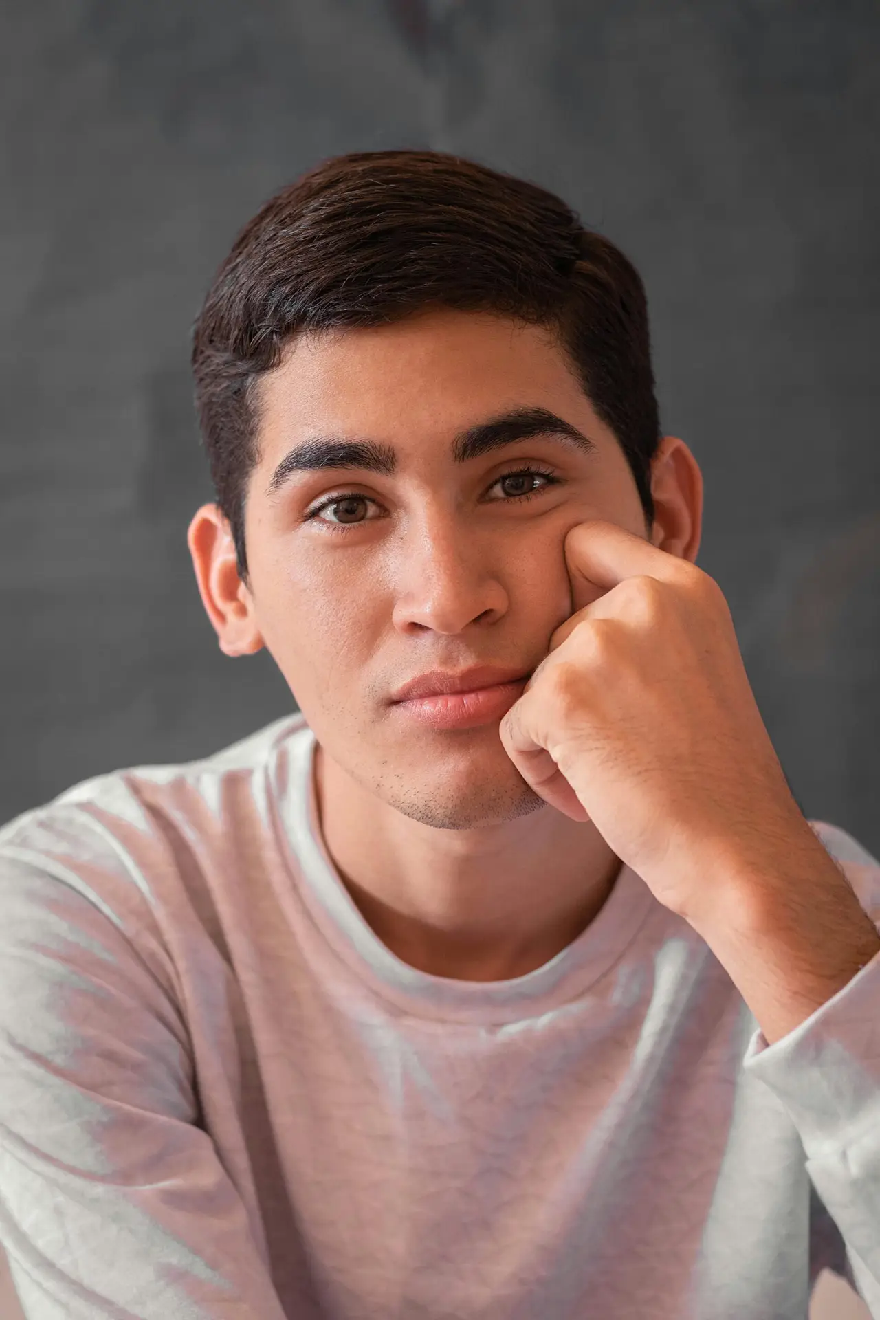 Close-up portrait of a young man posing indoors with a thoughtful expression.